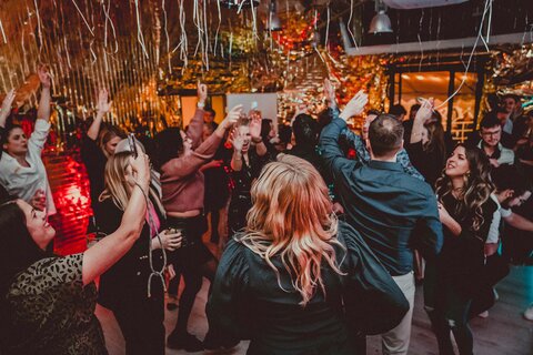 Captains Dinner bei wob | © wob AG Das Bild zeigt eine Gruppe Menschen, die zusammen auf einer Tanzfläche feiern. Die Stimmung ist ausgelassen. Glitzernde Girlanden hängen von der Decke. | © wob AG