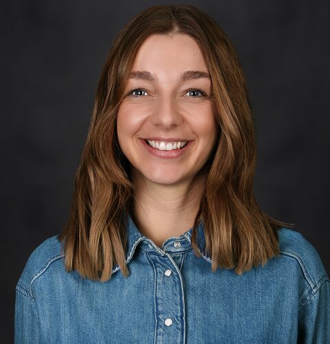 Vivien Paul Das Bild zeigt ein Porträt von Vivien Paul. Sie ist hat schulterlange blonde Haare, trägt ein Jeanshemd und lächelt freundlich in die Kamera.