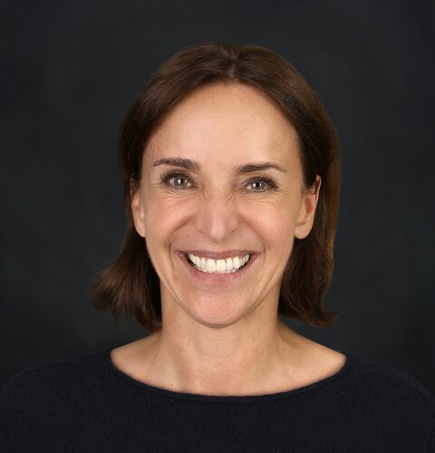 The picture shows a portrait of Sylvia Piske. She has dark hair that ends just above her shoulders. She smiles at the camera. She is wearing a black top. | © wob AG