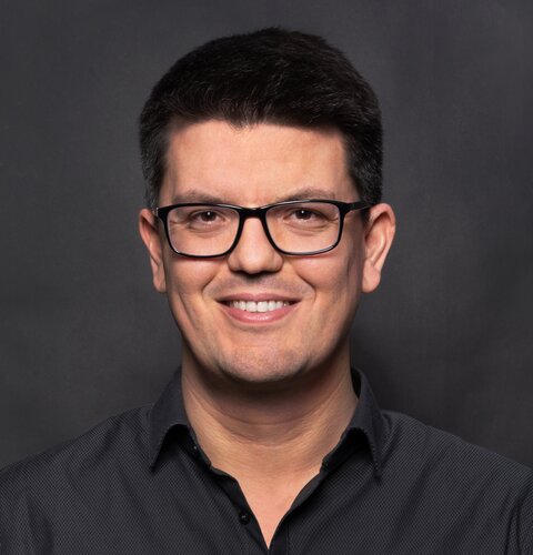 Das Bild ist ein Porträt von Jens Merkel. Er trägt eine Brille und ein dunkles Hemd. Der Hintergrund ist auch dunkel. | © wob AG